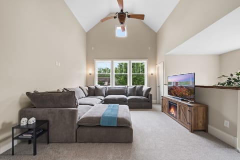 A cozy living room featuring a large sectional sofa, a fireplace, and windows that let in natural light.