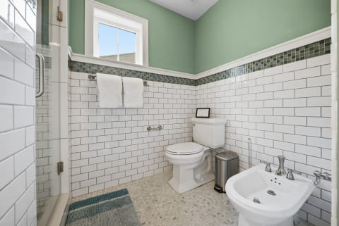 Contemporary bathroom with white subway tiles, green walls, and a glass shower.