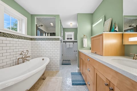 Luxurious bathroom with a soaking tub, walk-in shower, and dual vanities in pale green tones.