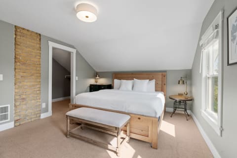 Inviting bedroom featuring a wooden bed, beige carpet, and natural light.
