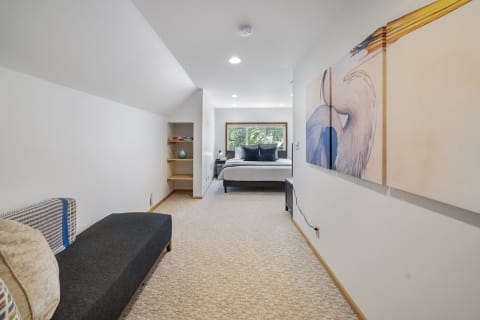 Bright bedroom with a lounge chair, bed, and bird-themed wall art.