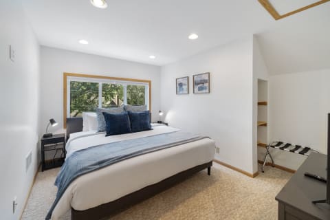 A modern and inviting bedroom featuring a large window, plush bedding, and decorative pillows.