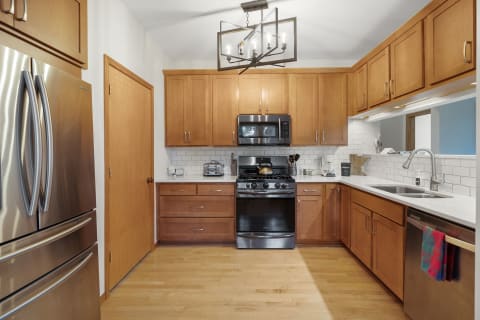 Interior view of a modern kitchen with wooden cabinets and stainless steel appliances.