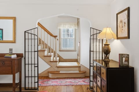 A cozy entrance with wooden staircase, decorative lamp, and a colorful rug.
