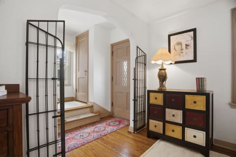 A well-decorated foyer featuring hardwood floors, artistic lamp, and a stylish cabinet with colorful drawers.