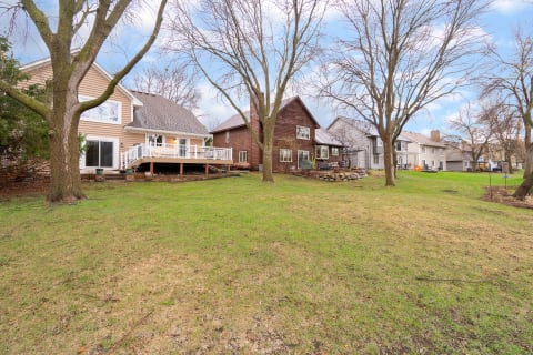 A row of homes with diverse designs, a green lawn, and bare trees under a blue sky.