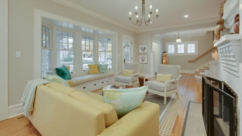 Bright living room with yellow sofa, two armchairs, large windows, and a cozy ambiance.