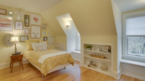 An attic bedroom featuring artistic wall decor, a yellow bedspread, and wooden furnishings.