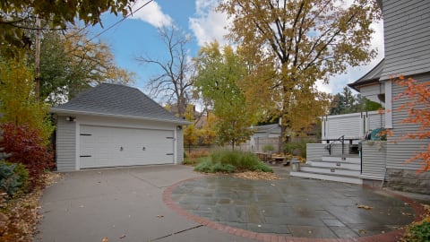 Suburban property featuring a driveway and outdoor area amidst colorful autumn trees.
