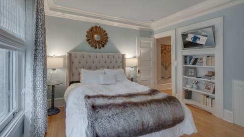 A cozy and elegant bedroom with a tufted bed, a faux fur throw, and warm ambient lighting.