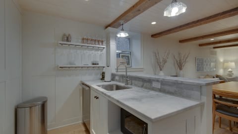 Cozy kitchen featuring marble countertops, white cabinetry, and wooden beams.