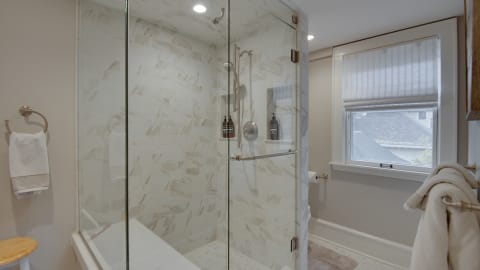 A luxurious bathroom featuring a glass-enclosed shower with marble tiles and elegant amenities.