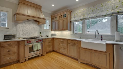 A modern kitchen featuring wood cabinetry, a farmhouse sink, and professional-grade appliances.