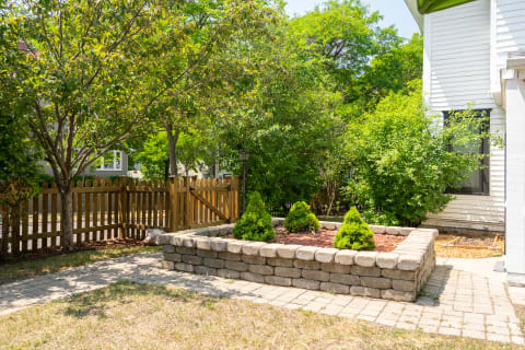 A landscaped yard featuring a stone retaining wall and lush trees.