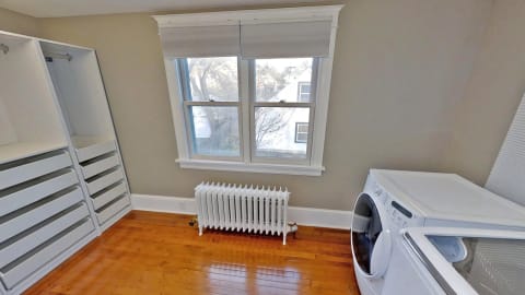 Bright organized laundry room with white storage shelves, washing machine, and large window.