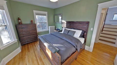 Cozy bedroom with a wooden bed, green walls, and hardwood floors.