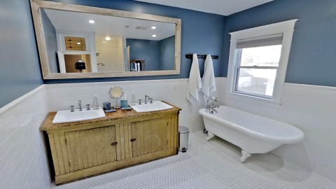 A well-designed bathroom with a wooden vanity, clawfoot bathtub, and blue walls.