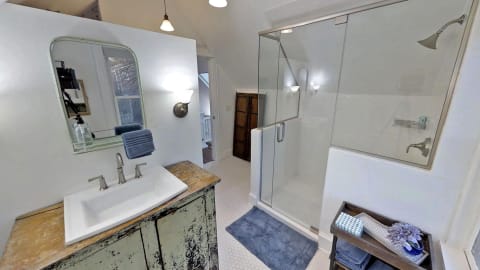 A stylish bathroom featuring a glass shower, a vintage vanity, and elegant decor.
