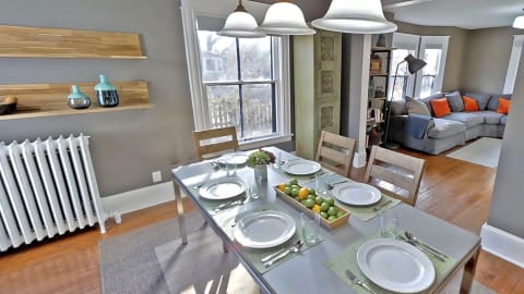A modern dining area with a glass table set for four, featuring decorative elements and fresh fruits.