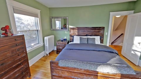 Cozy bedroom with green walls, wood furniture, and natural light.