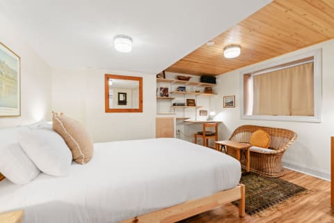 Cozy bedroom with a bed, rattan chair, and wooden shelves.