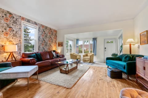 A cozy living room with a leather sofa, yellow armchairs, and floral wallpaper.