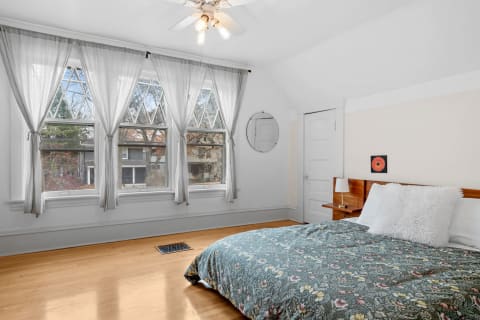 A bright bedroom featuring arched windows, floral bedding, and natural light.