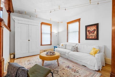 A bright living room with a white sofa, cozy throws, and vintage decor details.