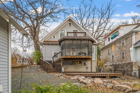 Charming gray cottage with a screened porch overlooking a quiet backyard and neighboring homes.
