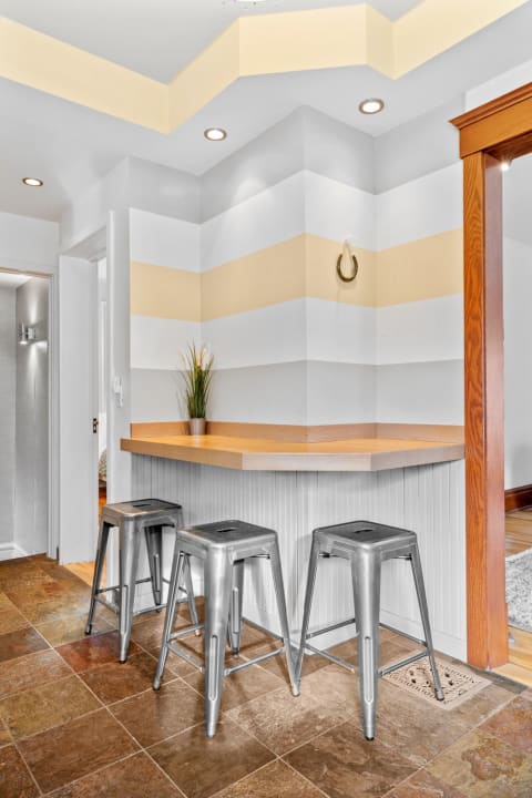 Modern breakfast bar with metallic stools and striped walls.