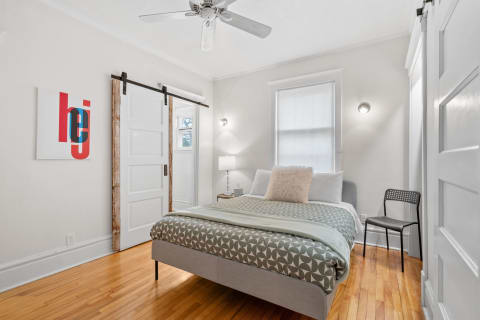 Cozy bedroom with hardwood floors, modern furnishings, and a rustic barn door.