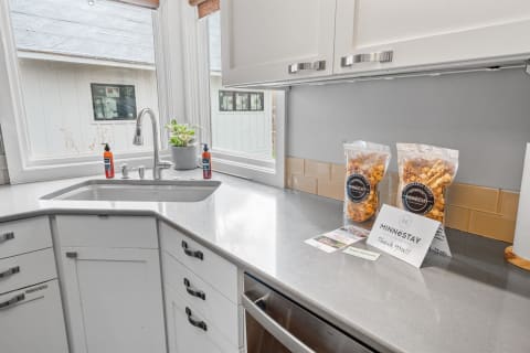 A sleek kitchen countertop with snacks and a welcome note, illuminated by natural light.