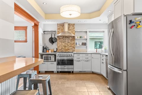 Modern kitchen with stainless steel appliances, mosaic tile backsplash, and a breakfast bar.