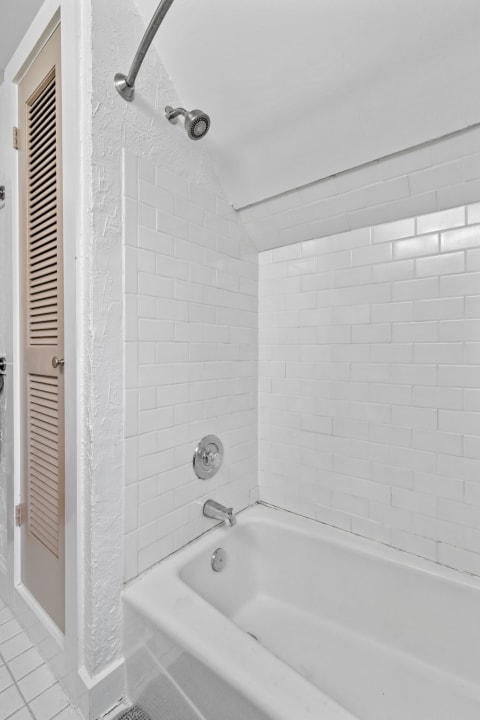 A clean and modern bathroom with white tiles and a tub-shower combo.
