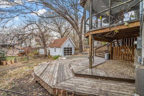 A multi-level wooden deck surrounded by trees and a small shed, perfect for outdoor relaxation.