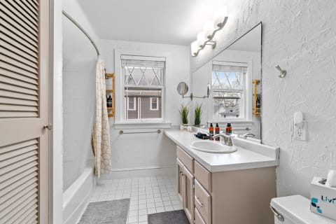 A spacious and modern bathroom with a soaking tub, a stylish vanity, and natural light from windows.