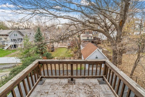 View from a wooden balcony looking out onto a peaceful neighborhood with trees and houses.