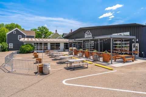 Outdoor seating area at Bad Weather restaurant, featuring picnic tables and a charming neighborhood backdrop.