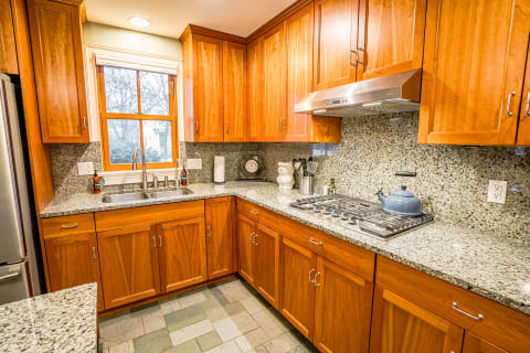 Inviting kitchen with wooden cabinets and granite countertops, featuring a sink and gas stove.