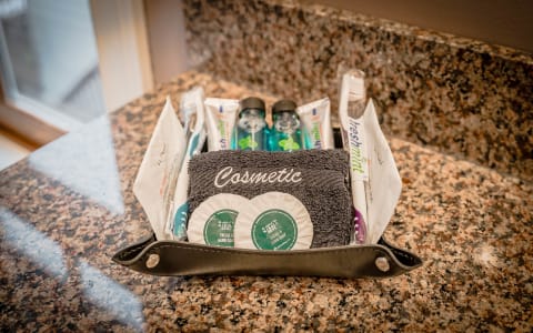 Curated toiletries displayed on a granite countertop, including soaps, a towel, and dental care items.