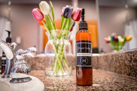 Sleek amber hand soap bottle on a granite countertop with a vase of colorful tulips in the background.