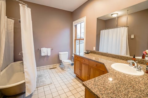 Spacious bathroom with tub-shower combo, granite countertops, and wooden cabinetry.