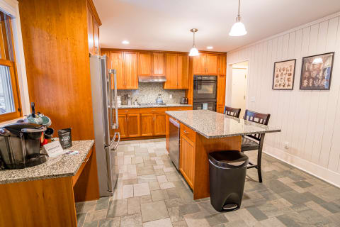 Modern kitchen with a granite island, wood cabinets, and stainless steel appliances.