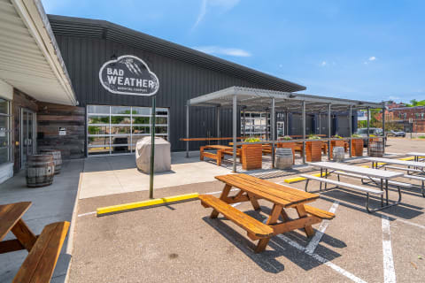 Outdoor seating area with picnic tables and a covered patio at Bad Weather Brewing Company.