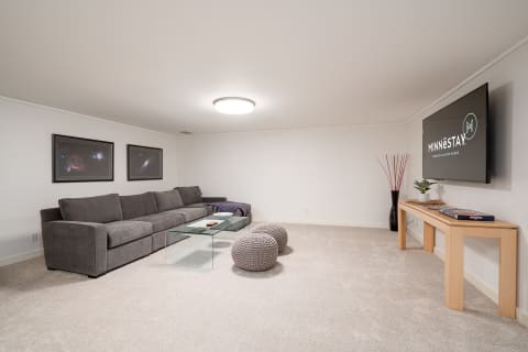 A cozy lounge area featuring a grey sectional, cosmic art, and a glass coffee table.