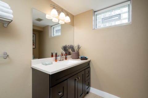 A modern bathroom with marble countertops, warm lighting, and lavender decor.
