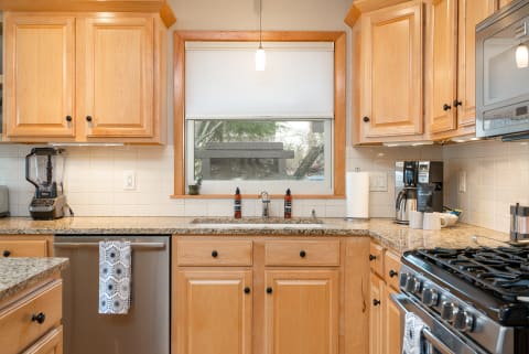 A cozy kitchen with warm wood cabinetry, granite countertops, and stainless steel appliances bathed in natural light.