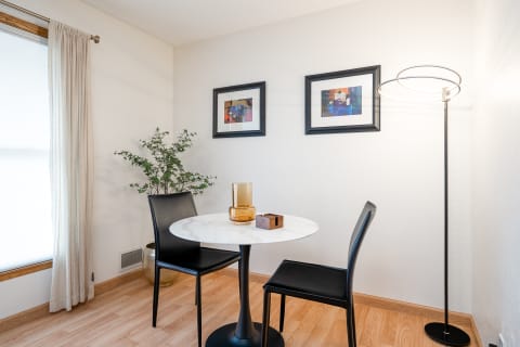 A small dining area featuring a marble table, black chairs, and artistic decorations.