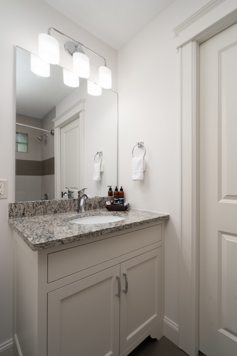 Modern bathroom with granite countertop and elegant lighting fixtures.