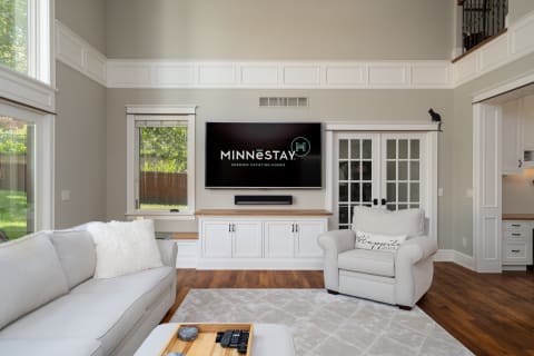 Spacious living room featuring a modern TV, light gray sofa, and a black cat sitting on the doorframe.